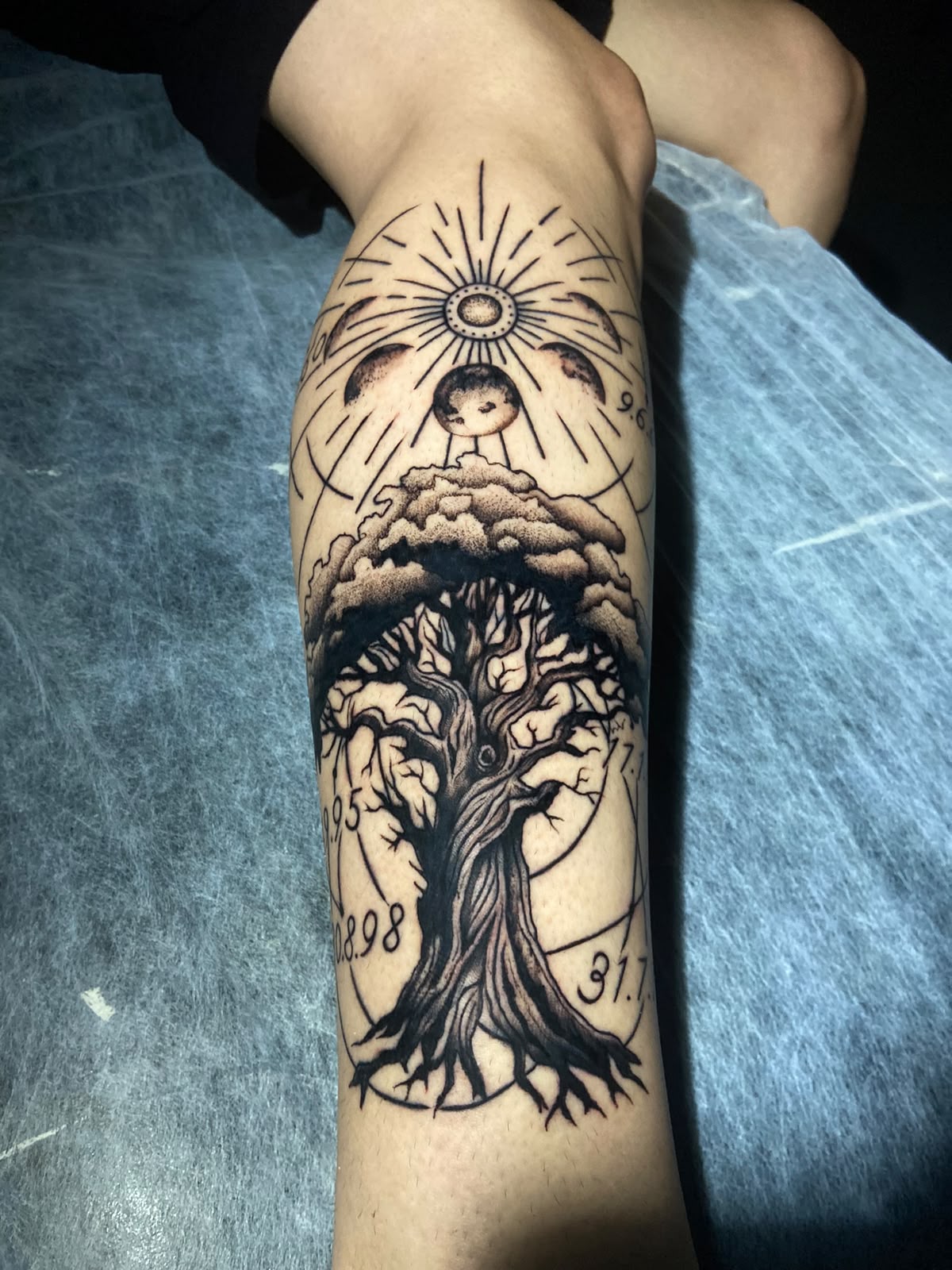 Tatuagem de árvore com sol, lua e datas no antebraço