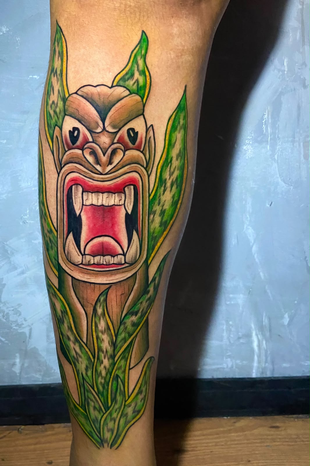 Tatuagem colorida inspirada em carranca e folhagem